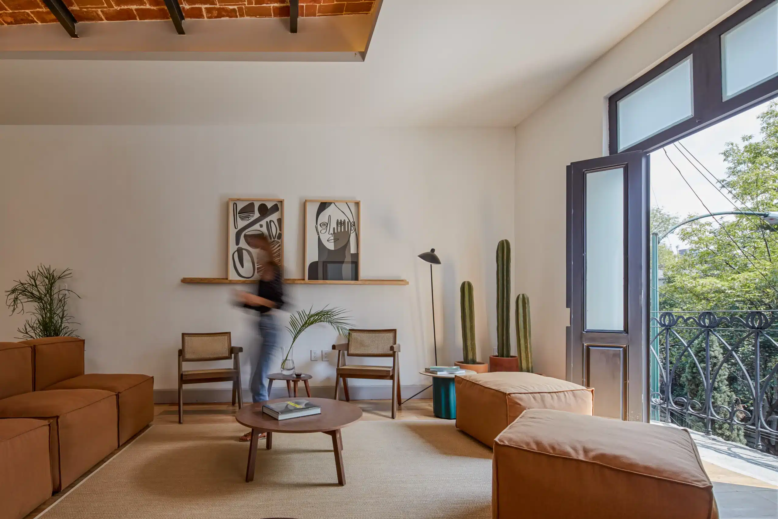 Sala interior de un coliving en colores terracota con balcón a la calle